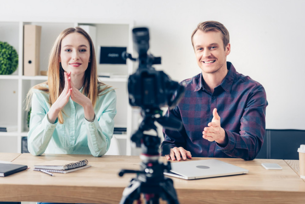 man and woman recording video using camera on tripod